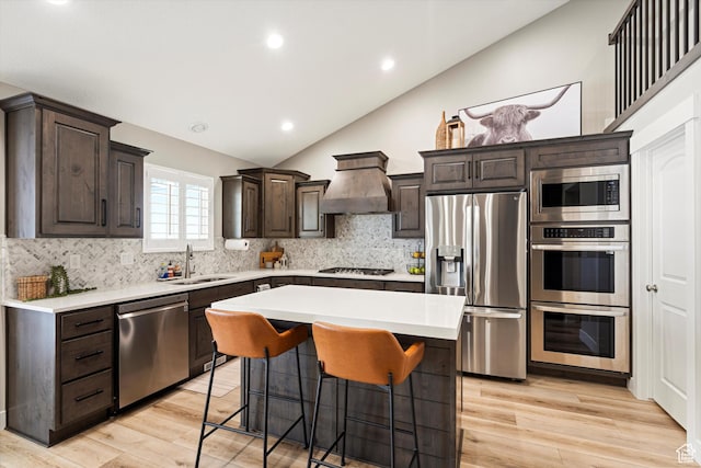 kitchen with custom exhaust hood, a sink, light countertops, dark brown cabinets, and appliances with stainless steel finishes