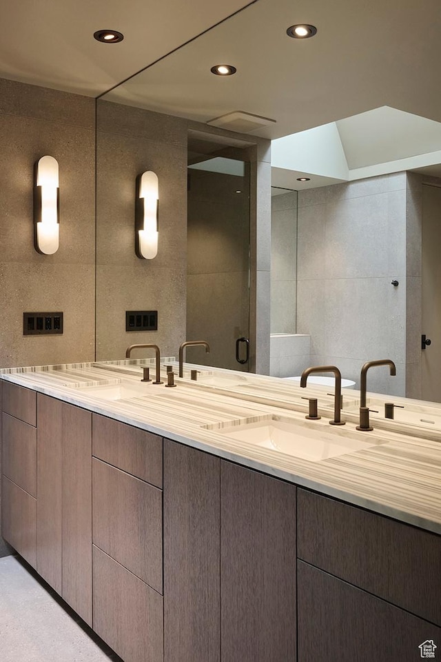 bathroom featuring double vanity, tile walls, a sink, and recessed lighting