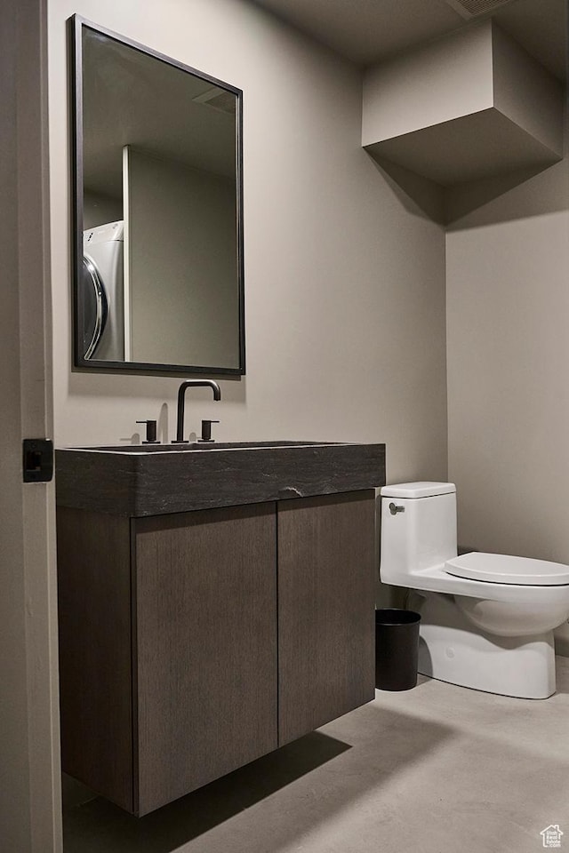 half bathroom with toilet, washer / clothes dryer, and vanity