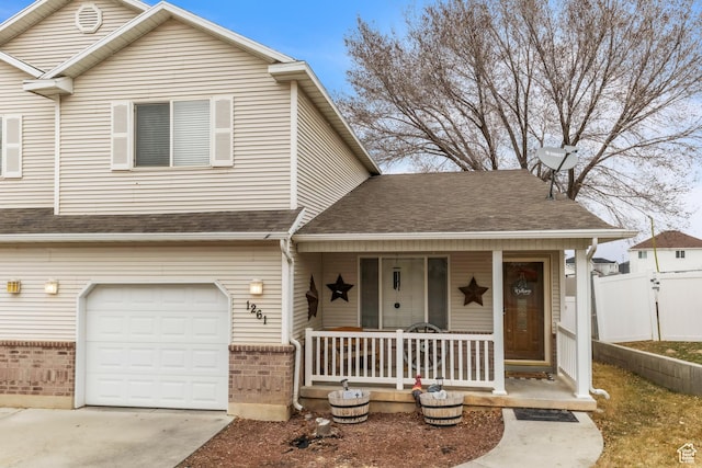 view of front of house with a shingled roof, an attached garage, fence, a porch, and brick siding