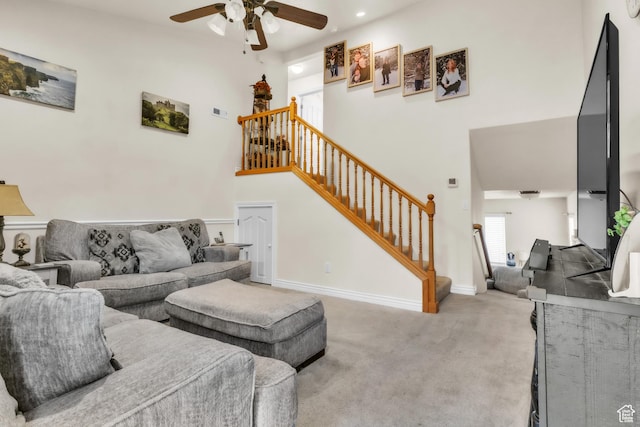living area with stairs, a high ceiling, baseboards, and light colored carpet