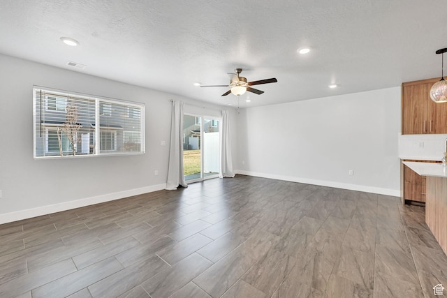 6512 S 390 E, South Weber, UT 84405 - unfurnished living room with ceiling fan, a textured ceiling, visible vents, and baseboards