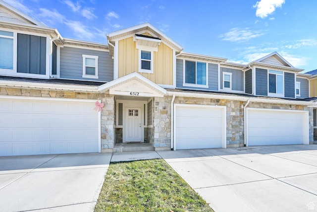 multi unit property featuring a garage, driveway, board and batten siding, and stone siding