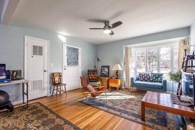 living room featuring wood finished floors, a ceiling fan, and an office area