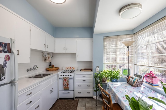 kitchen with white appliances, a sink, light countertops, and white cabinets