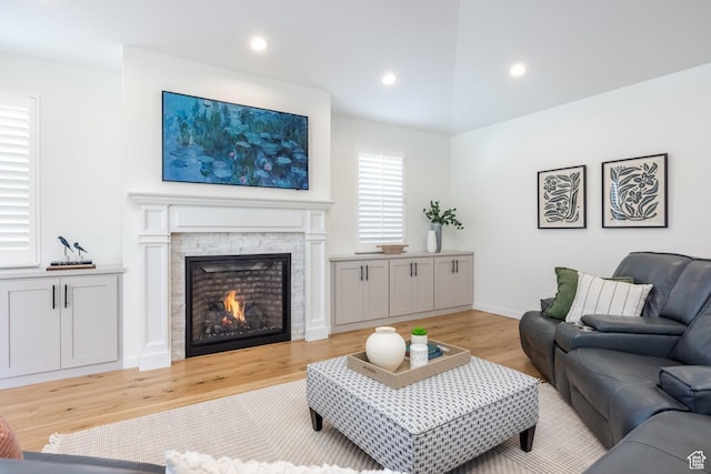 living room featuring light wood-type flooring, a fireplace, recessed lighting, and baseboards