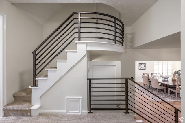 stairs featuring carpet, baseboards, and high vaulted ceiling