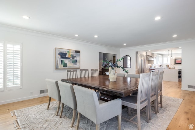 dining area with ornamental molding, light wood finished floors, recessed lighting, and baseboards