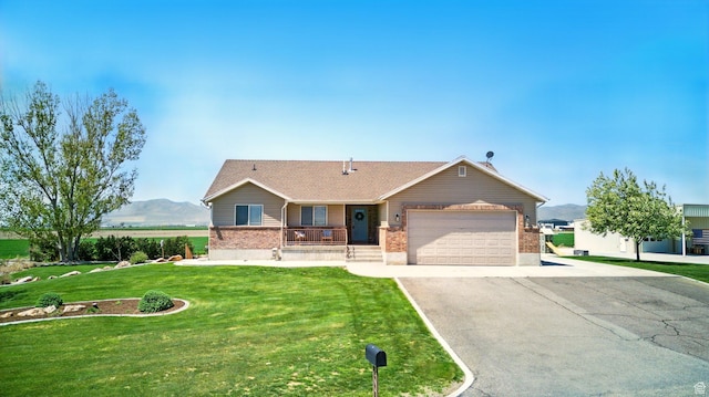 10285 N 7600 W, Tremonton, UT 84337 - ranch-style house with an attached garage, covered porch, aphalt driveway, a front yard, and brick siding