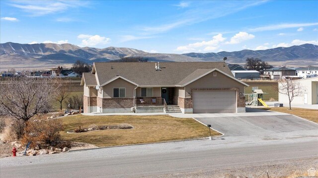 10285 N 7600 W, Tremonton, UT 84337 - single story home featuring a porch, an attached garage, a mountain view, driveway, and a front lawn