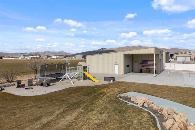10285 N 7600 W, Tremonton, UT 84337 - rear view of house featuring playground community, a trampoline, a yard, fence, and a patio area
