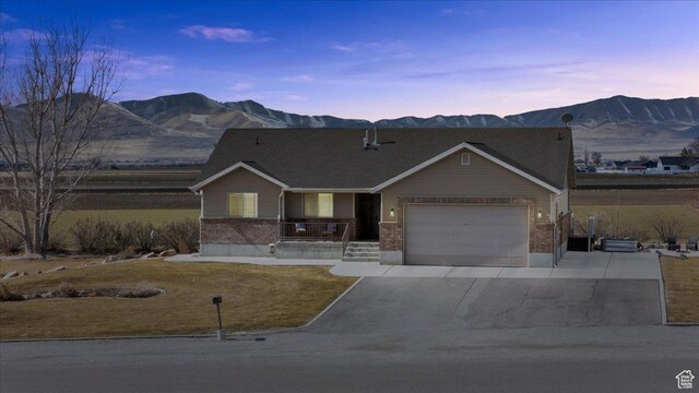 10285 N 7600 W, Tremonton, UT 84337 - single story home featuring covered porch, a mountain view, brick siding, concrete driveway, and a garage