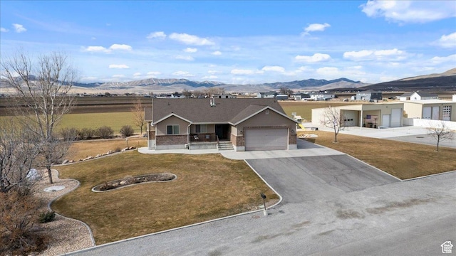 10285 N 7600 W, Tremonton, UT 84337 - ranch-style house featuring brick siding, a mountain view, an attached garage, aphalt driveway, and a front lawn