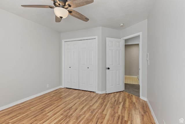 unfurnished bedroom with a closet, ceiling fan, light wood-type flooring, and baseboards