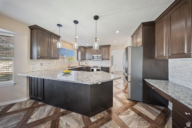 kitchen featuring dark brown cabinetry, a peninsula, stainless steel appliances, and baseboards