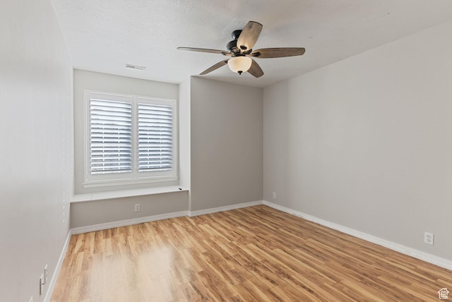 spare room featuring visible vents, baseboards, light wood-style flooring, and a ceiling fan