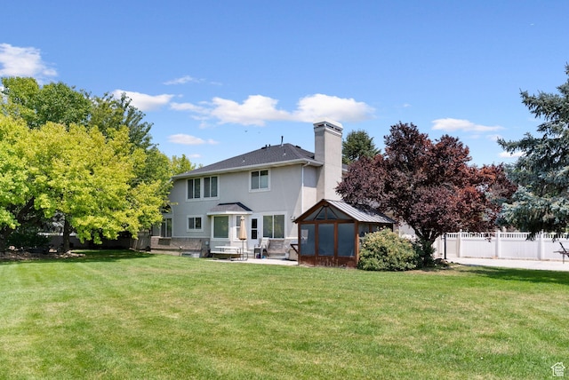 rear view of house featuring a patio area, a chimney, a yard, and fence