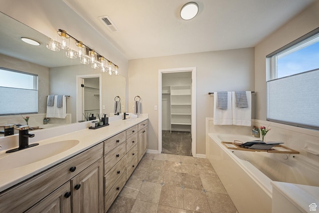 bathroom featuring a wealth of natural light, double vanity, a bath, and a sink