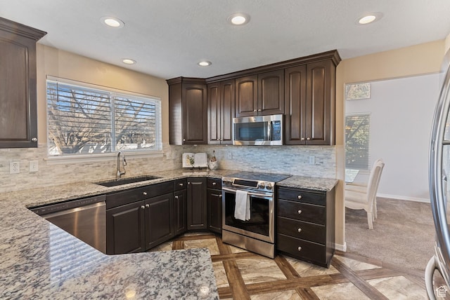 kitchen featuring backsplash, appliances with stainless steel finishes, light stone countertops, and a sink
