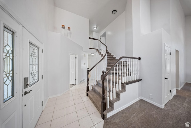 entrance foyer featuring tile patterned floors, plenty of natural light, stairs, and a high ceiling