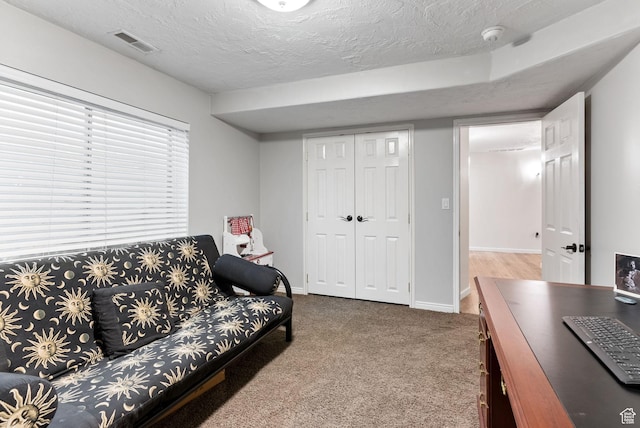 carpeted living area with visible vents, baseboards, and a textured ceiling