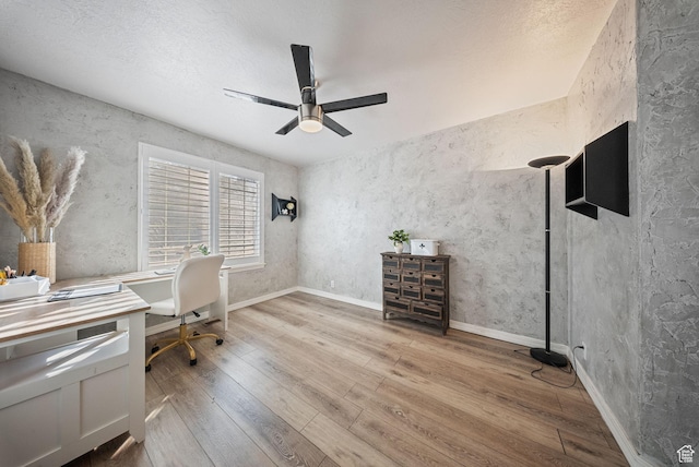 unfurnished office featuring baseboards, wood-type flooring, and a ceiling fan