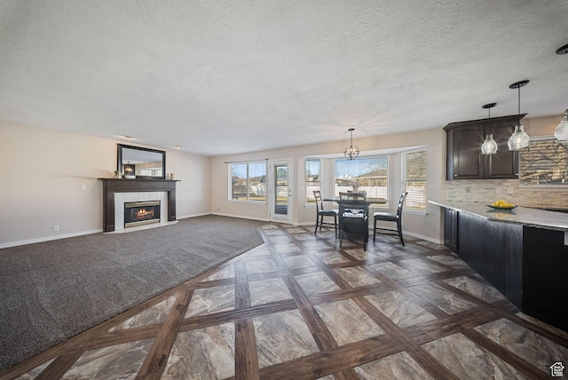 interior space with decorative backsplash, a fireplace, pendant lighting, and baseboards