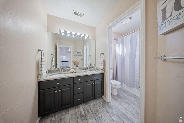 full bathroom with a sink, visible vents, toilet, and wood finished floors