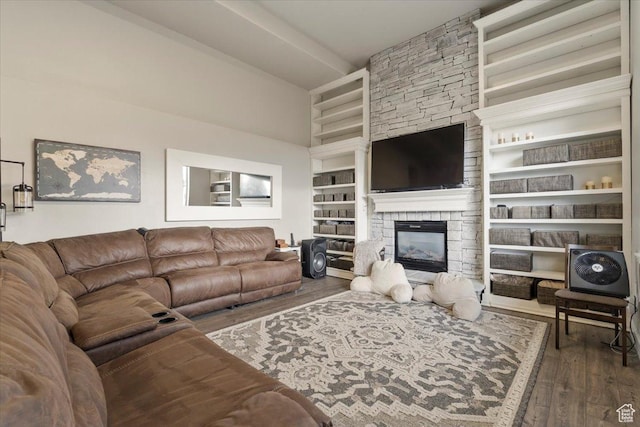 living room with built in features, a fireplace, a towering ceiling, and wood finished floors