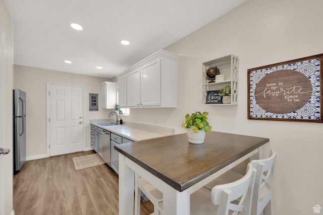 kitchen featuring recessed lighting, light wood-style flooring, appliances with stainless steel finishes, white cabinets, and a sink