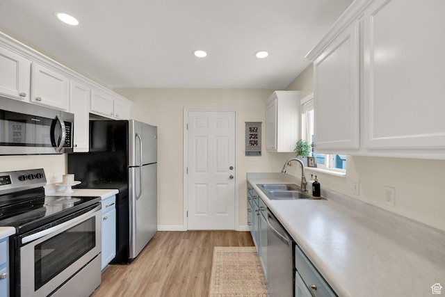 kitchen with white cabinetry, stainless steel appliances, light countertops, and a sink