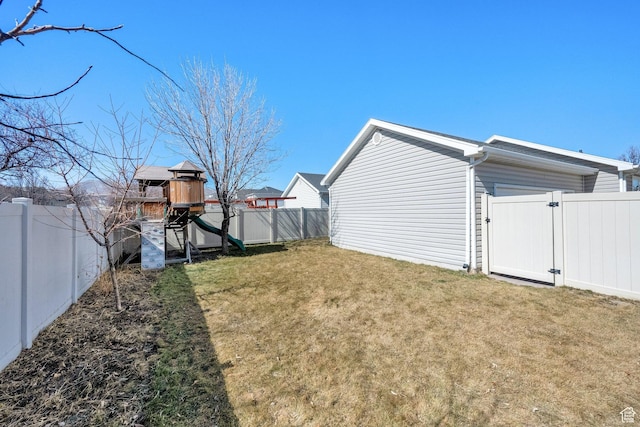 view of yard with a gate, a fenced backyard, and a playground