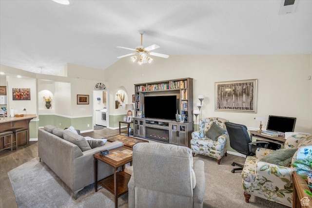 living room featuring a ceiling fan, vaulted ceiling, baseboards, and wood finished floors