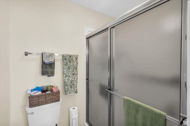 bathroom featuring a shower with shower door and toilet
