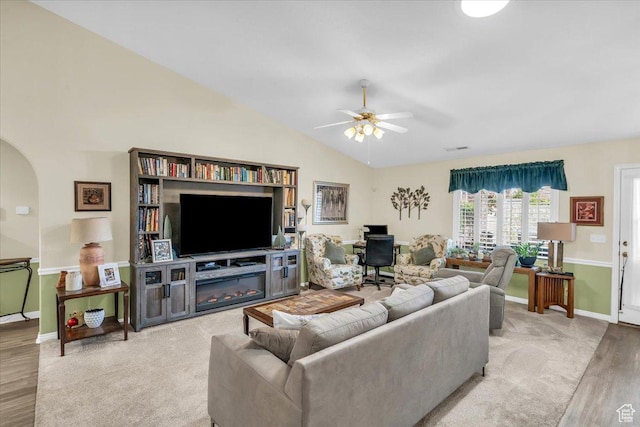 living room with arched walkways, vaulted ceiling, ceiling fan, wood finished floors, and baseboards