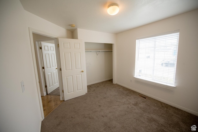 unfurnished bedroom with a closet, carpet floors, visible vents, and baseboards