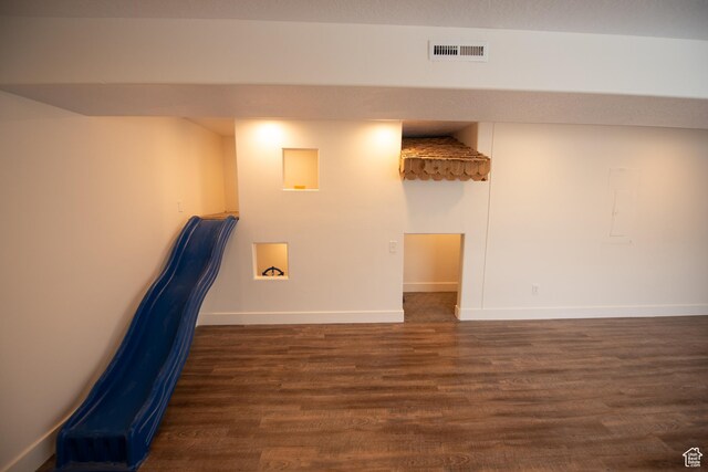 below grade area with baseboards, wood finished floors, and visible vents