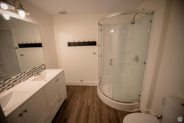 full bathroom with a sink, a stall shower, visible vents, baseboards, and wood finished floors