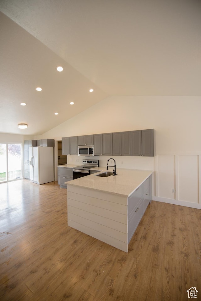 kitchen featuring a sink, light wood-style floors, gray cabinetry, a peninsula, and appliances with stainless steel finishes