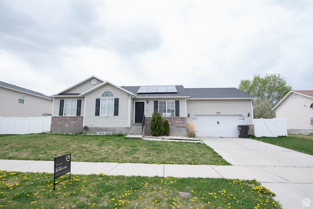 ranch-style house featuring a garage, concrete driveway, fence, a front yard, and solar panels