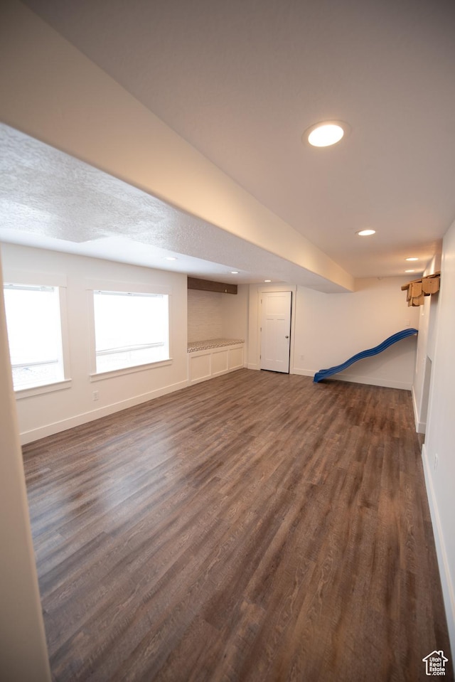basement featuring baseboards, dark wood-style flooring, and recessed lighting