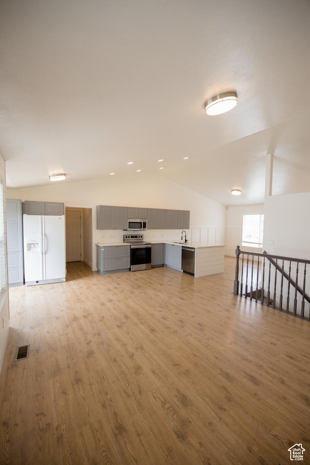 interior space featuring vaulted ceiling, light wood finished floors, a sink, and visible vents