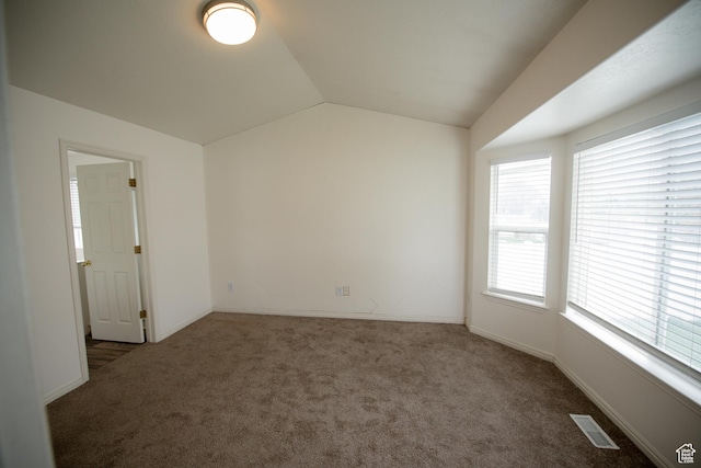 spare room featuring vaulted ceiling, visible vents, carpet flooring, and baseboards