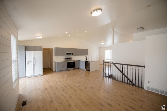 unfurnished living room featuring visible vents, light wood finished floors, high vaulted ceiling, and a sink