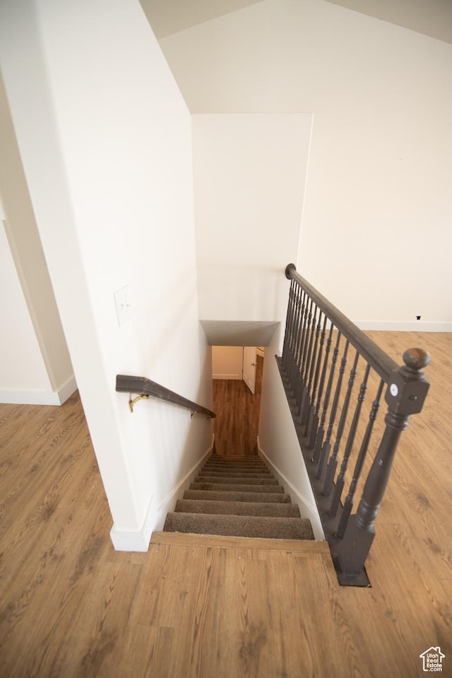 stairs featuring vaulted ceiling, baseboards, and wood finished floors