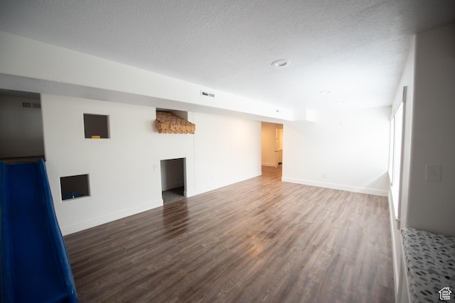 unfurnished living room with visible vents, baseboards, wood finished floors, and a textured ceiling