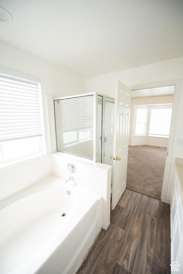 bathroom with a shower stall, a garden tub, and wood finished floors