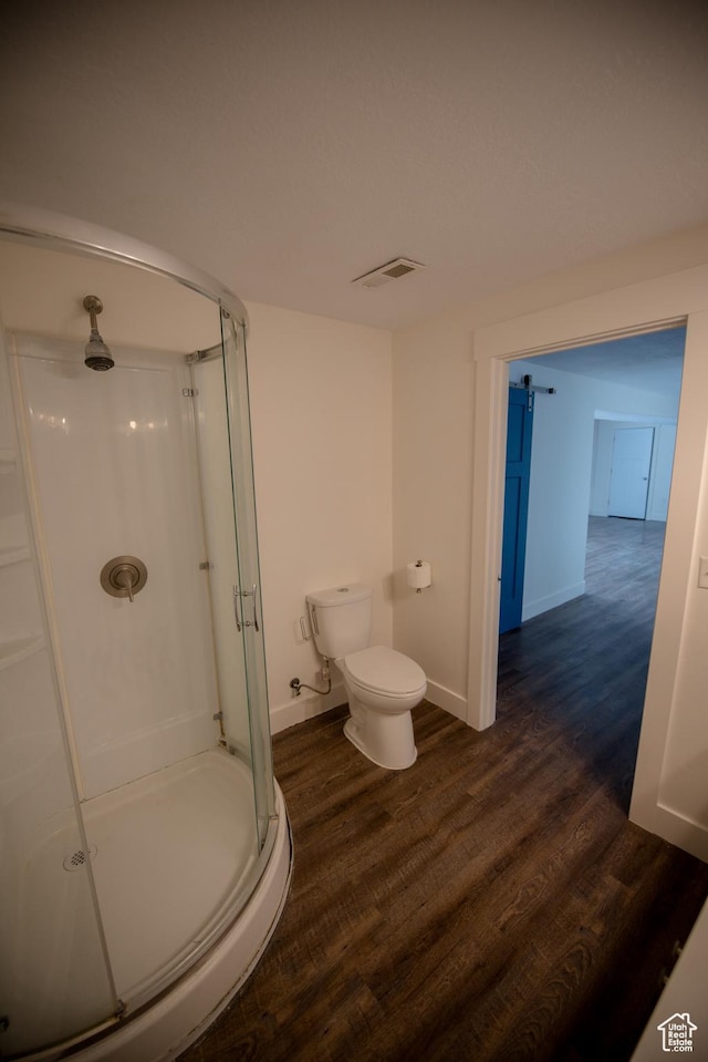 bathroom featuring a shower stall, toilet, wood finished floors, and visible vents