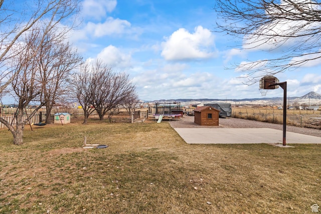 79 S 250 E, Aurora, UT 84620 - view of yard featuring a trampoline, a storage unit, a mountain view, fence, and an outdoor structure