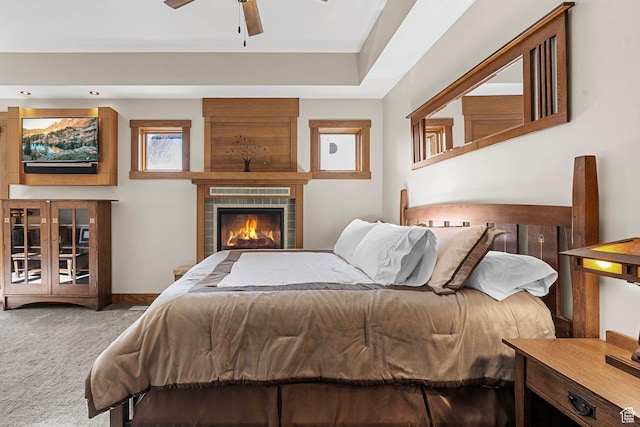 bedroom with a ceiling fan, baseboards, carpet, and a fireplace